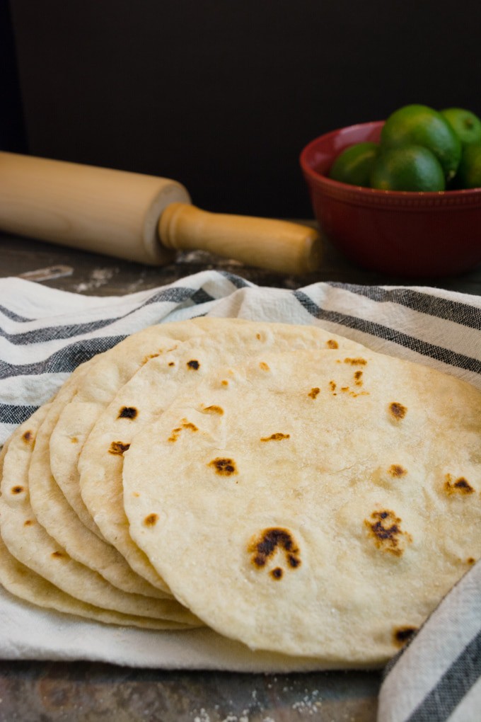 A stack of homemade flour tortillas on a towel.