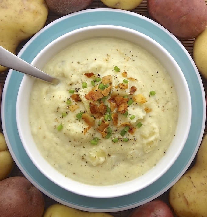 A bowl of vegan creamy potato cauliflower soup topped with coconut bacon and green onions.