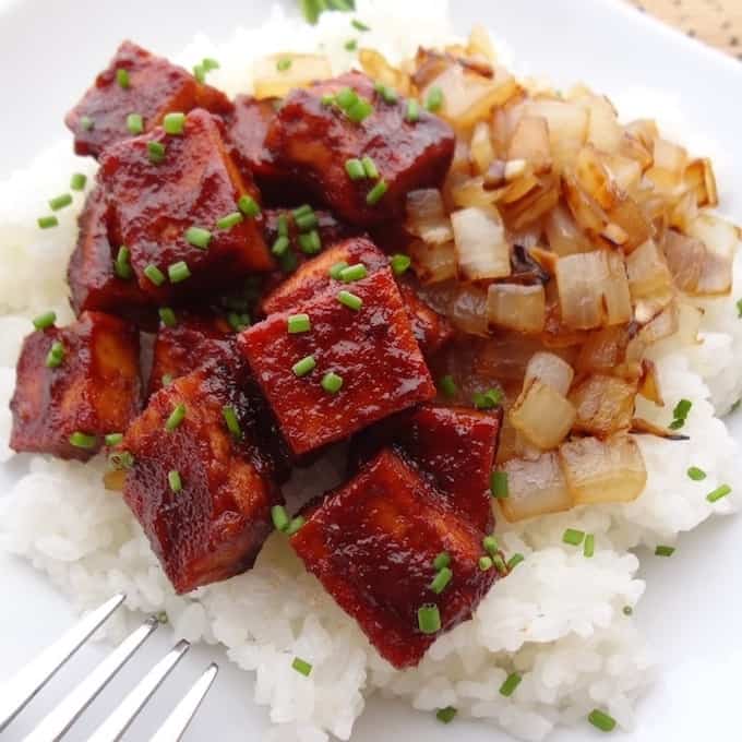 Square cuts of bbq tofu and caramelized onions on top a bed of white rice.