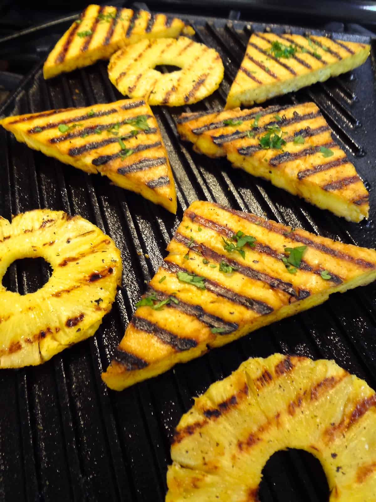 Grilled lemon tofu and pineapple rings with grill marks on a pan.