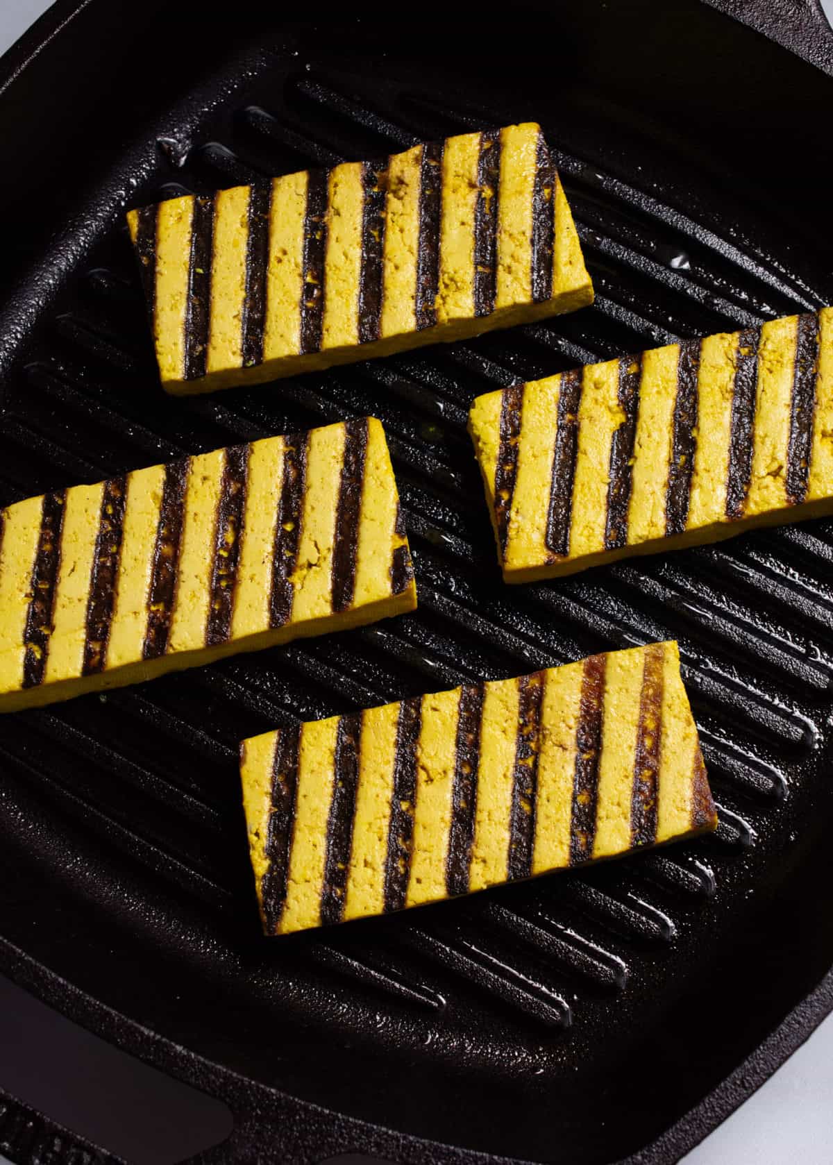 Tofu cooking in a grilling cast iron skillet.