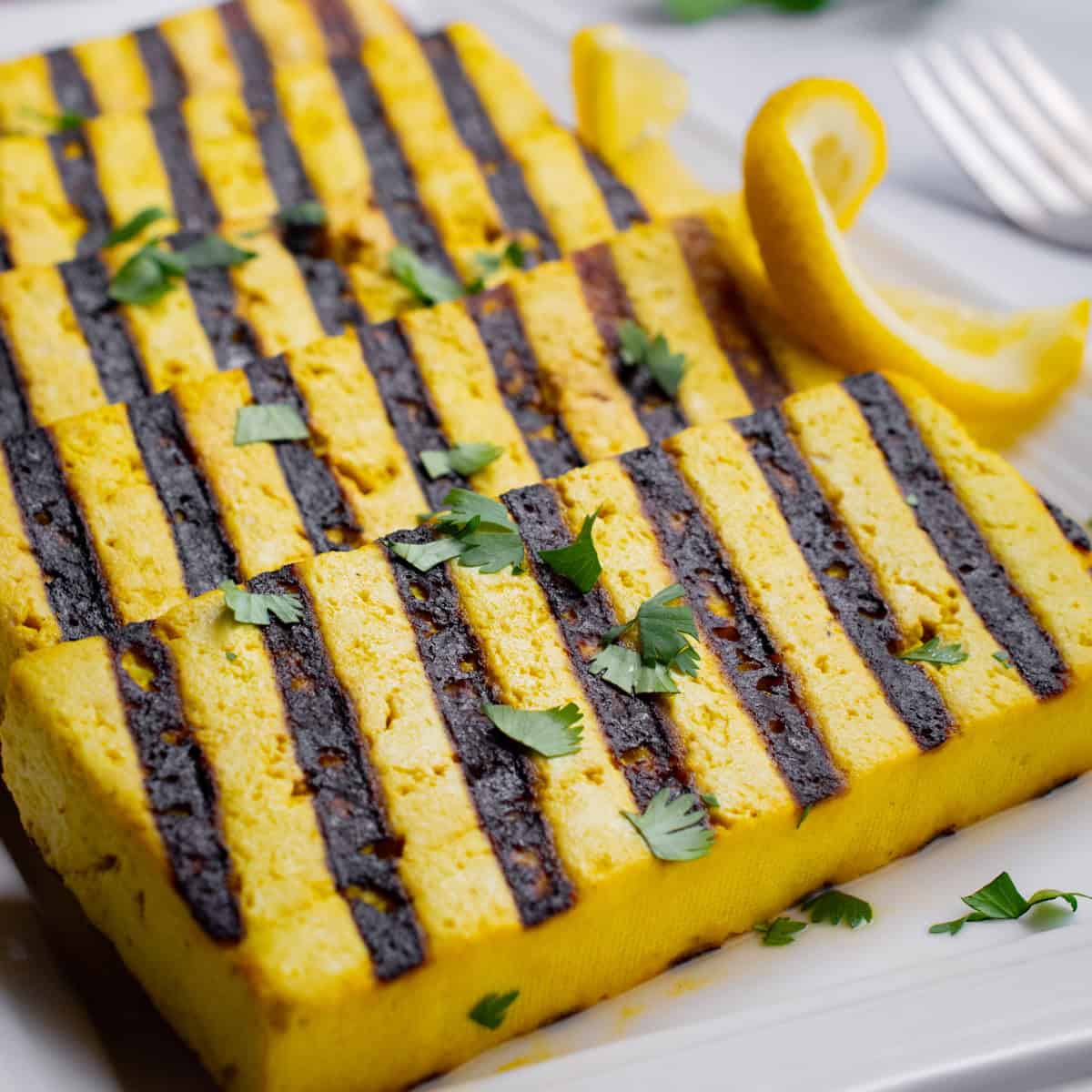 Slices of grilled lemon tofu on a serving plate.