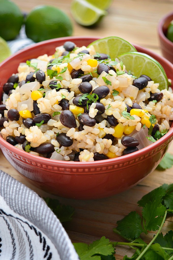 A dinner bowl of black beans and lime rice with lime wedges.