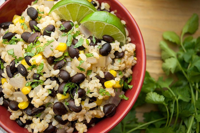 A bowl of black beans and lime rice with lime wedges.