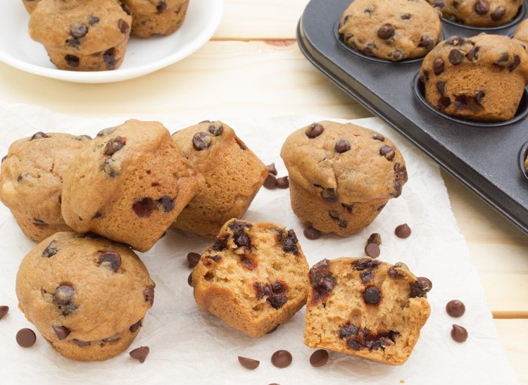 Mini Vegan Chocolate Chip Muffins on parchment paper with one broke open.