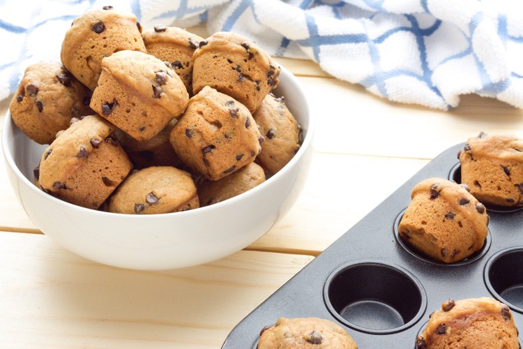 A muffin pan and white bowl with mini Vegan Chocolate Chip Muffins.