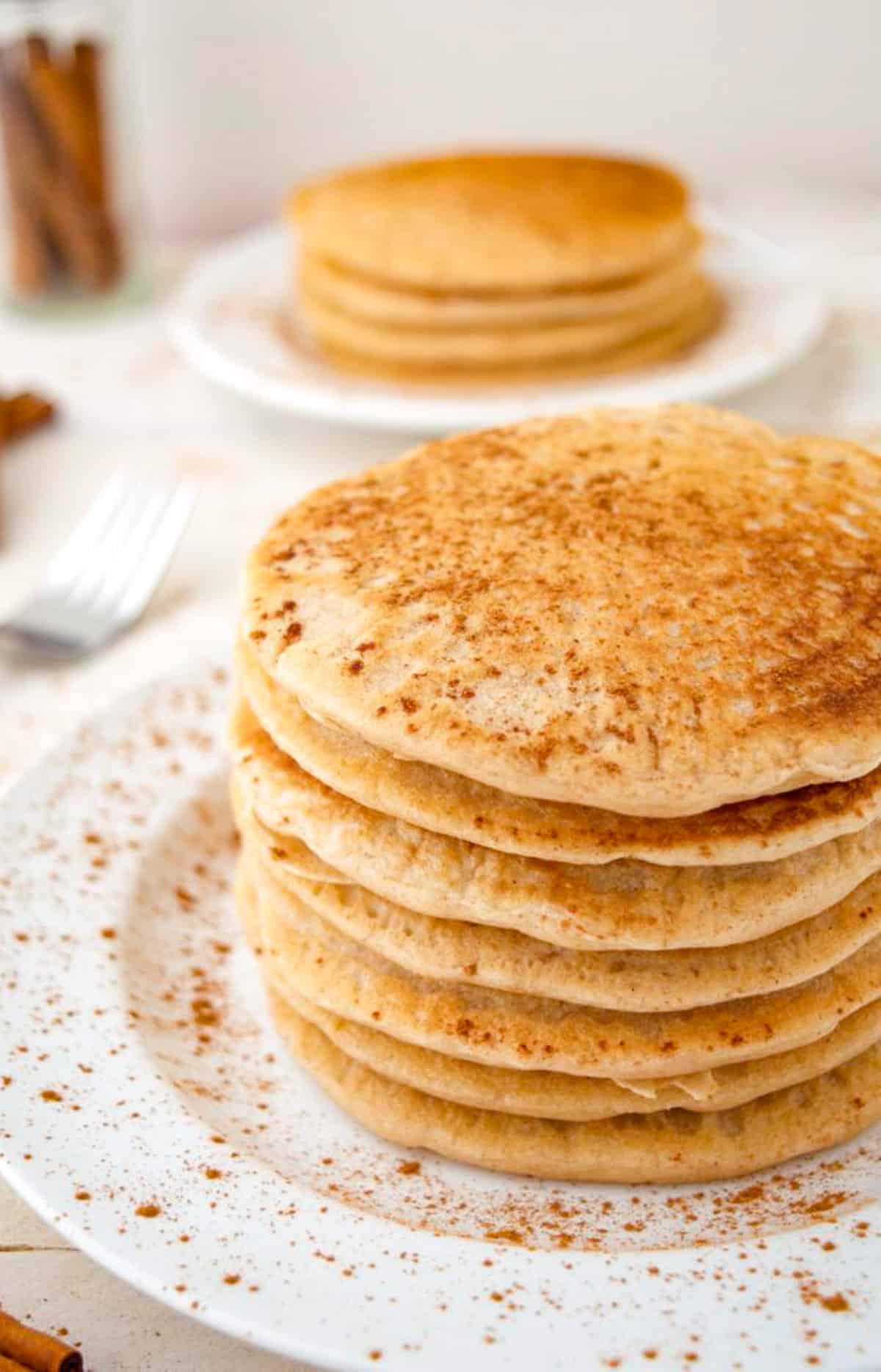 A stack of cinnamon pancakes on a white plate.