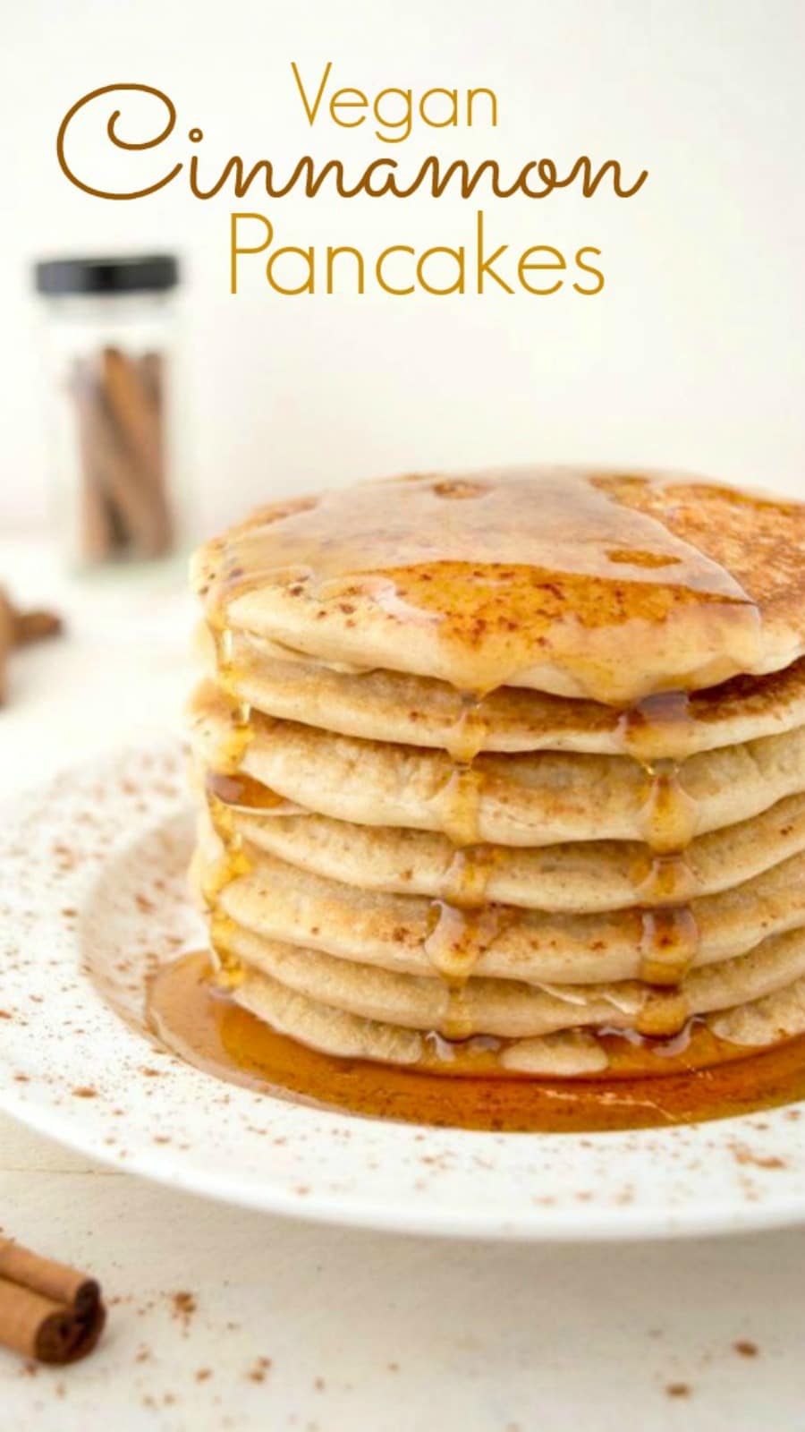 A stack of vegan cinnamon pancakes on a white plate topped with maple syrup.