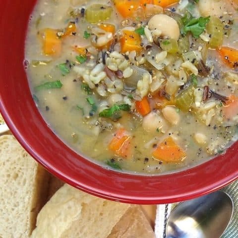 A bowl of wild rice soup served with french bread.