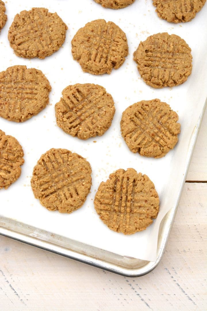 A baking sheet lined with white parchment paper and peanut butter cookies after baking.
