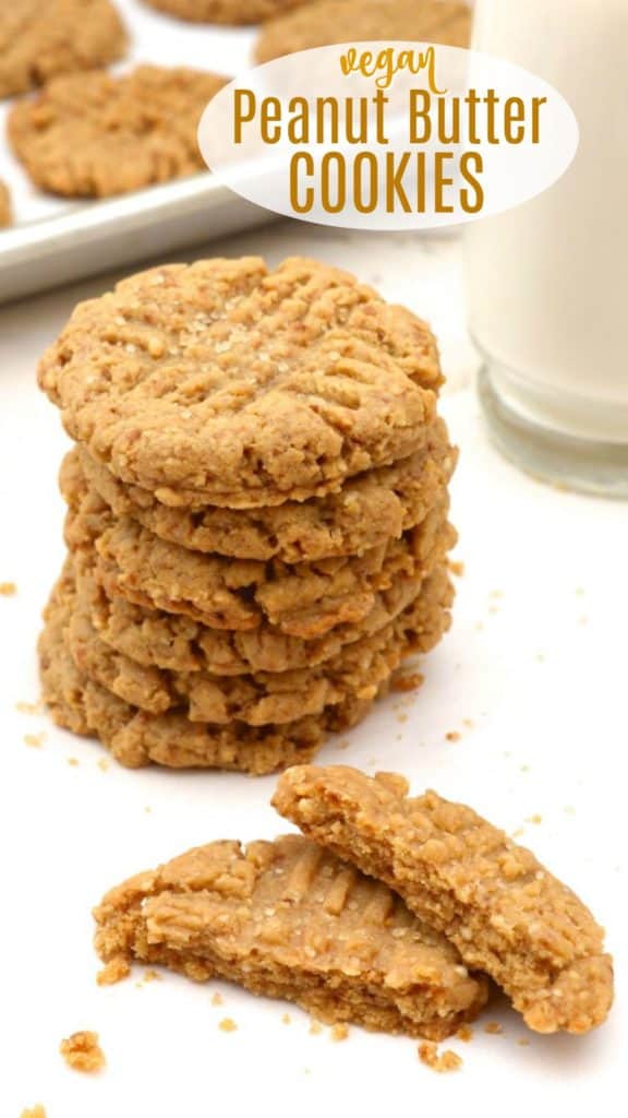 6 vegan peanut butter cookies stacked and one broken with a glass of almond milk.