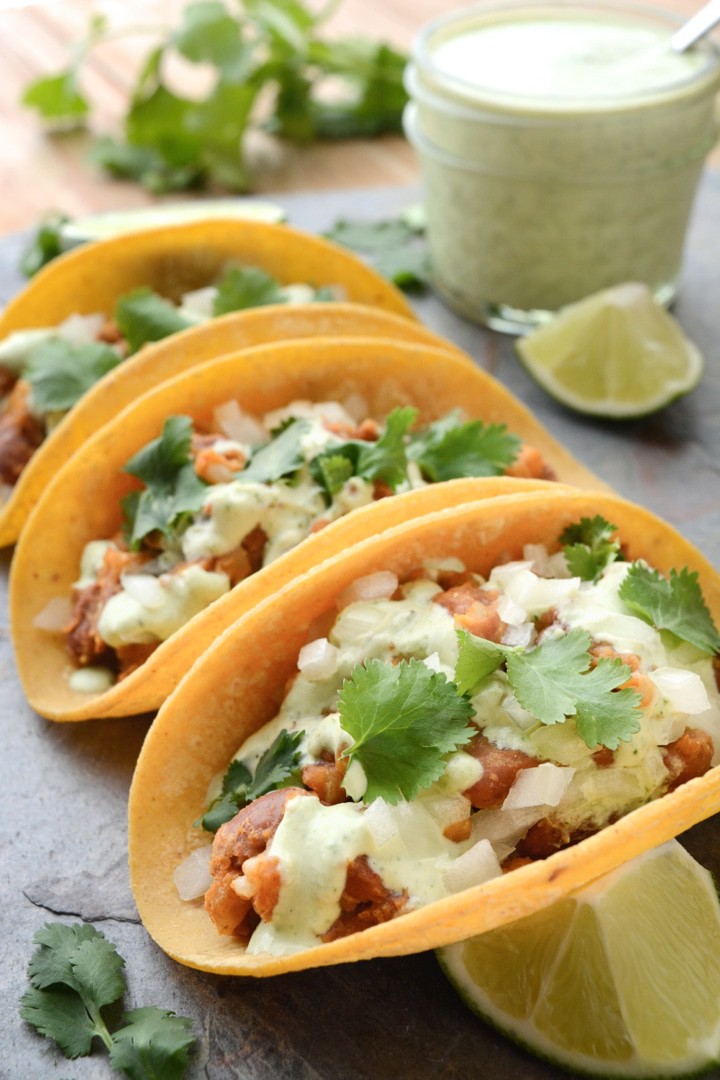 Vegan Tacos with Cilantro Lime Sauce are gluten-free and oil-free. These healthy 20 minute tacos are so easy to make and only take one pan! The filling is made with seasoned pinto beans and rice. Then the tacos are topped with a tangy cilantro lime sauce.