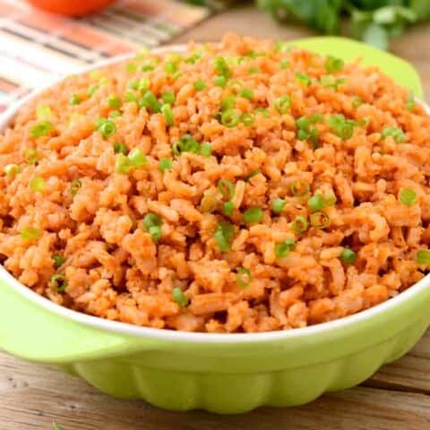 Spanish rice in a green bowl with handles.