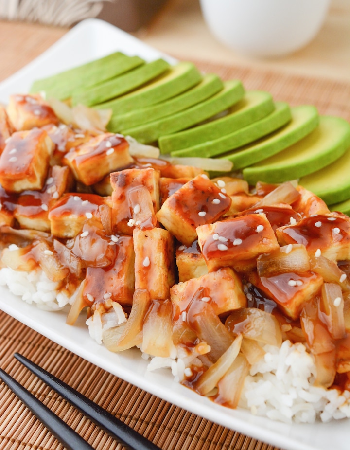 Teriyaki Tofu on a bed of white basmati rice with caramelized onions and avocado slices.