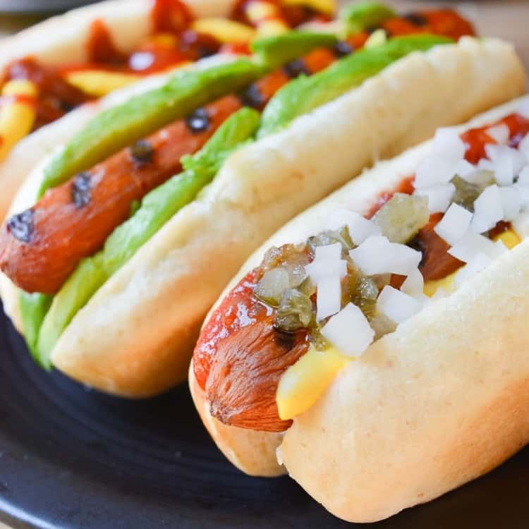 A carrot hot dog topped with mustard. ketchup, relish, and diced onion.