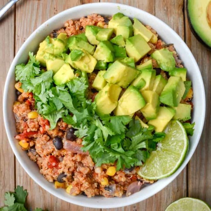 Mexican quinoa bowl topped with fresh cilantro, diced avocado, and a lime wedge.