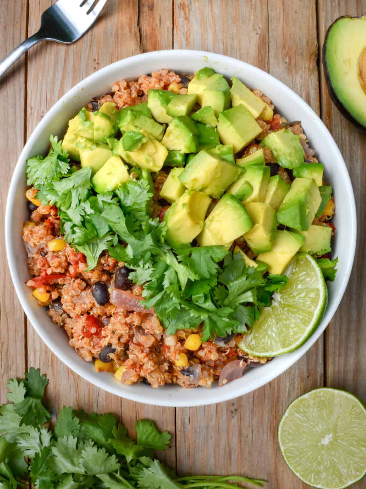 Quinoa with tomatoes, black beans, and corn topped with fresh cilantro, diced avocado, and a lime wedge.