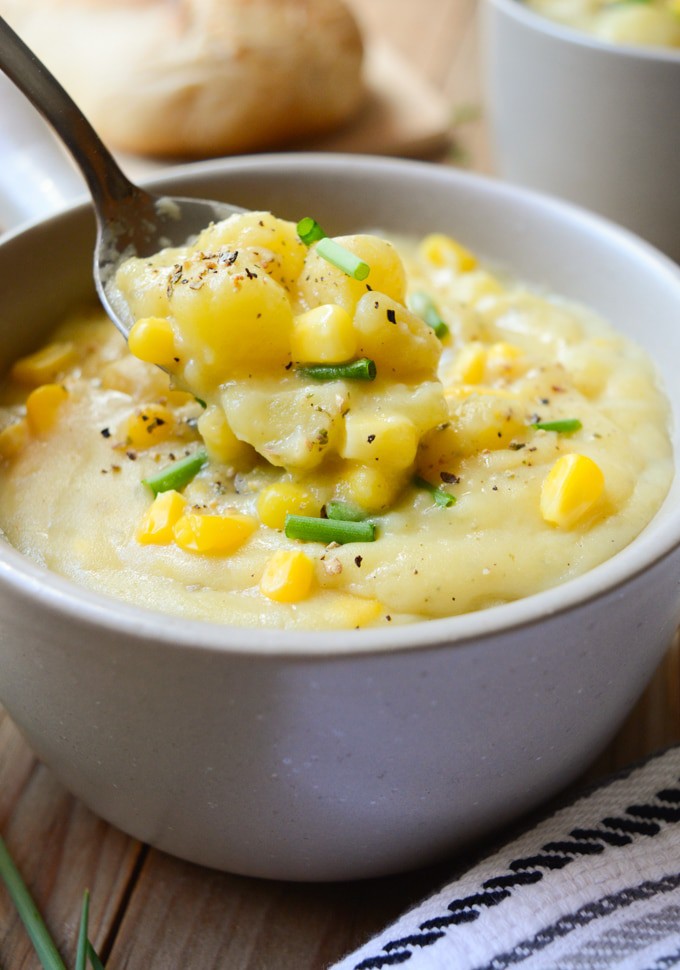 A spoon digging into chunky Vegan Potato Corn Chowder.