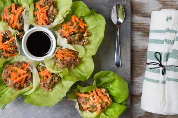 Top view of vegan lettuce wraps. Butter lettuce leaves filled with a 'umami' lentil-walnut mix. Served with a side of Asian-inspired sauce.