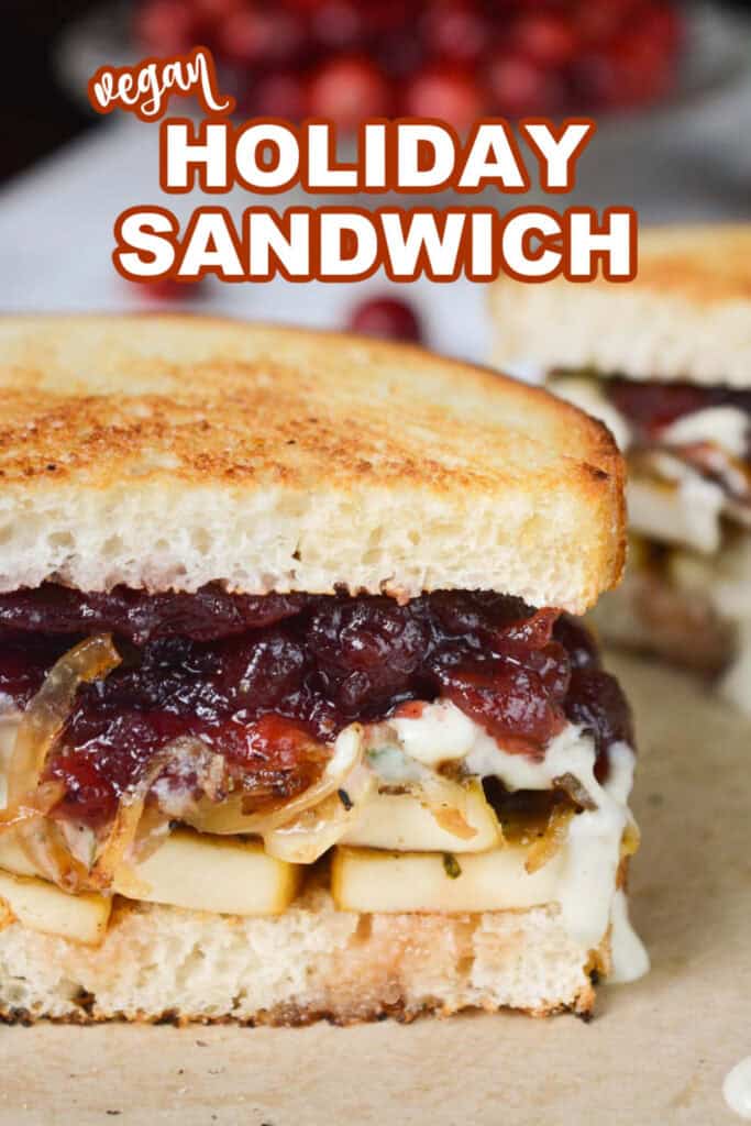 Sandwich with marinated tofu, caramelized onions, herb dressing, and cranberry sauce with the writing "vegan holiday sandwich".