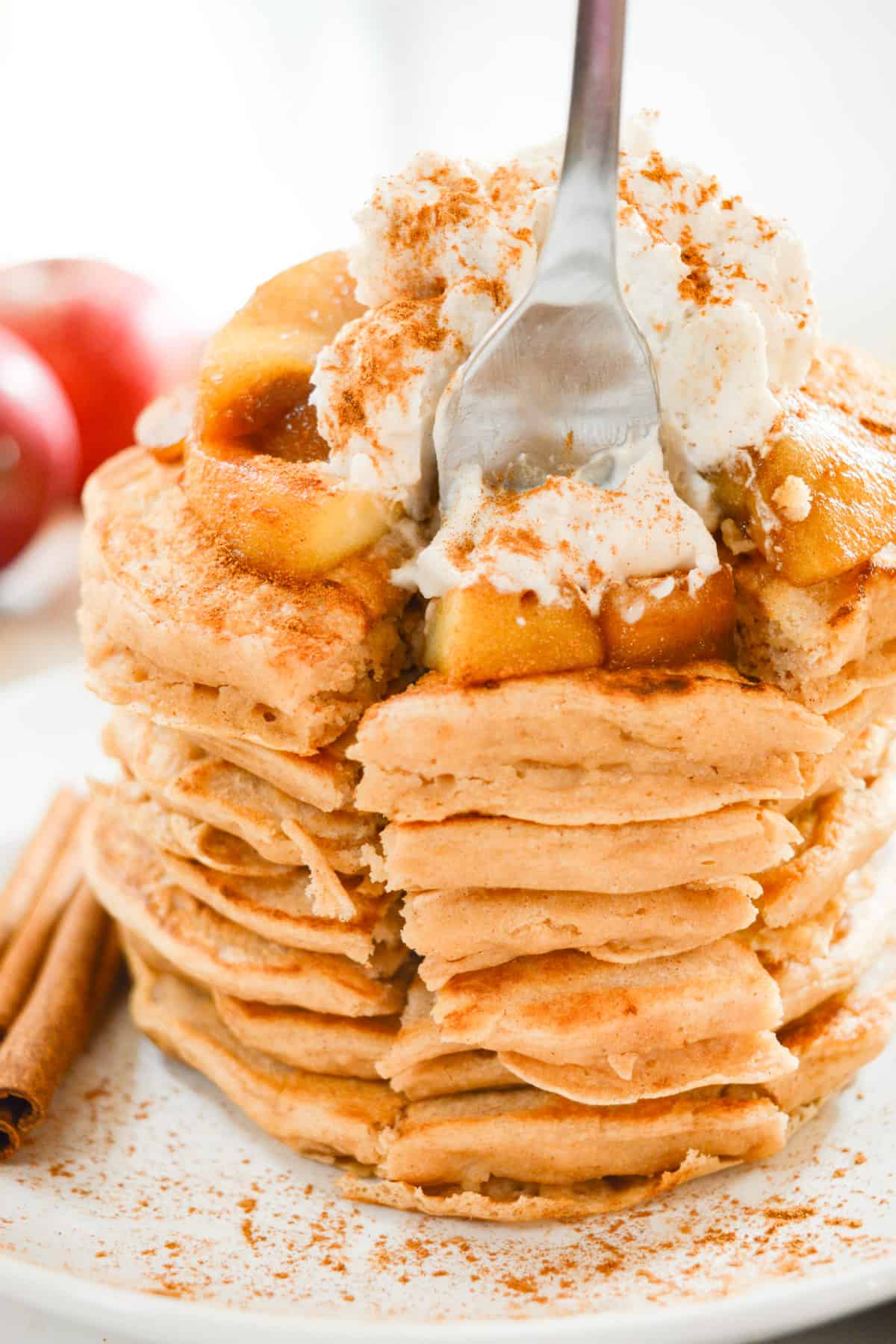 A stack of vegan apple cinnamon pancakes with a bite cut out.