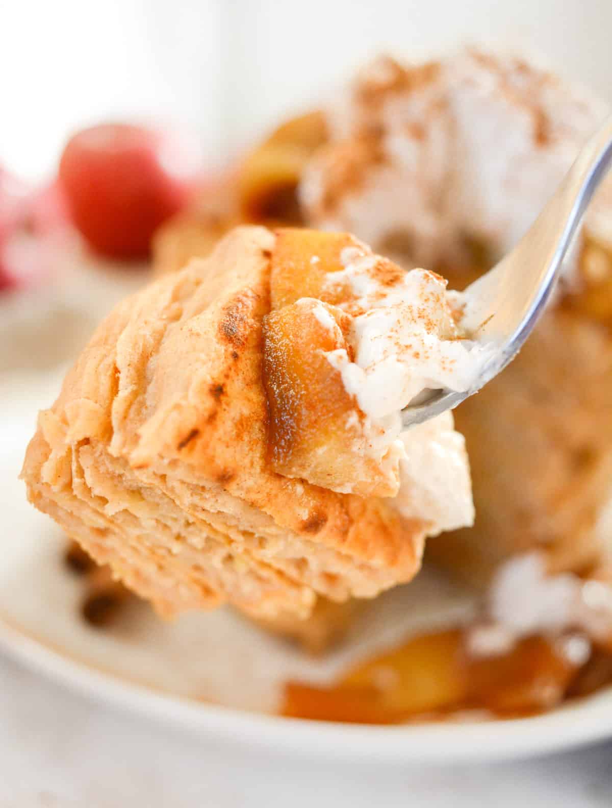 A bite of vegan topped with cooked apples and coconut whip on a fork.