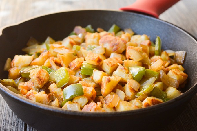 side angle of breakfast potatoes with onions and bell peppers in a skillet.