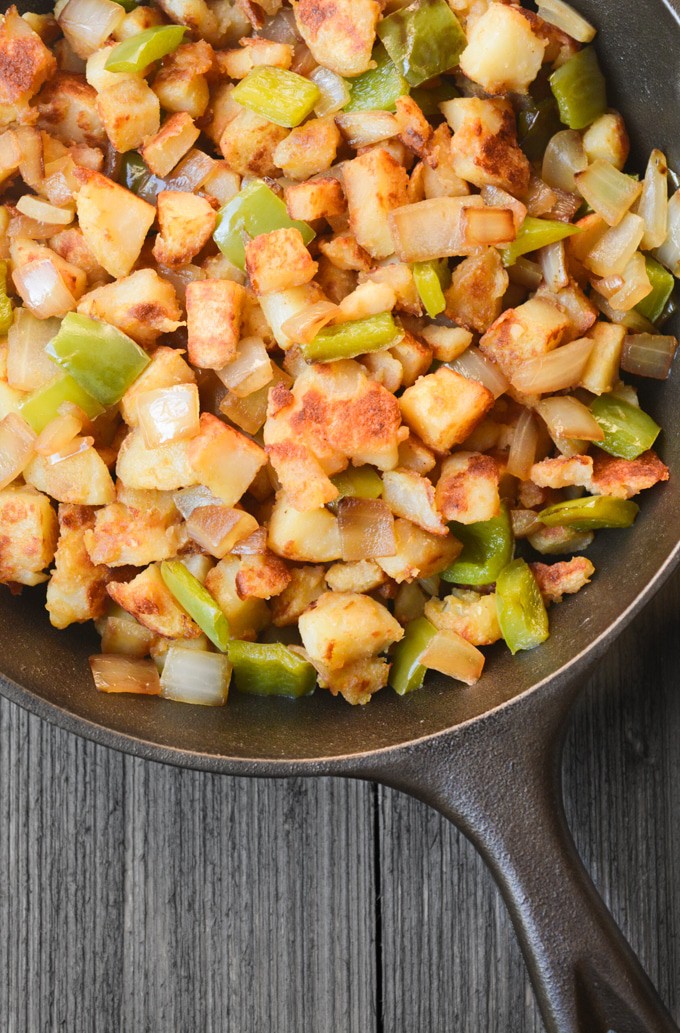 Breakfast potatoes browned in a skillet with bell peppers and onion.