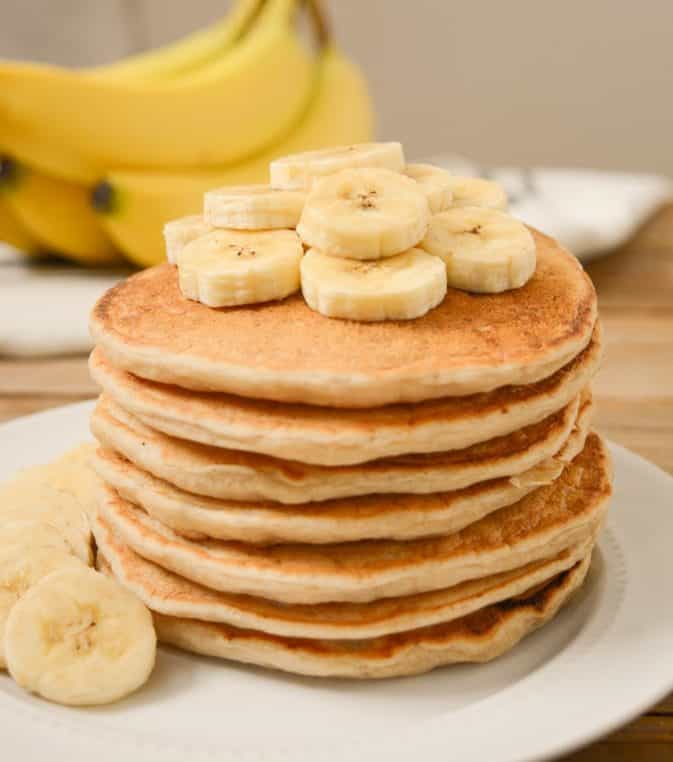 Stack of banana milk pancakes with sliced bananas on top.