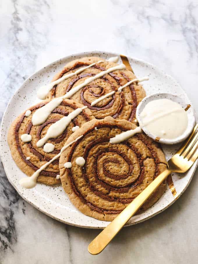 Vegan cinnamon roll pancakes topped with icing.
