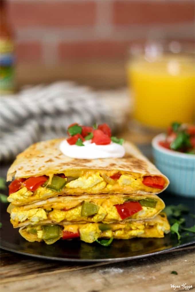 Vegan Breakfast Quesadilla cut into 3 triangles and stacked on a black plate.