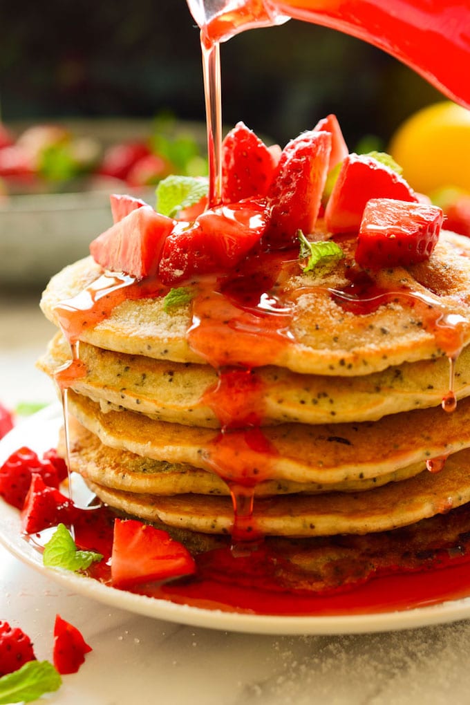 A stack of strawberry lemon pancakes topped with fresh strawberries.