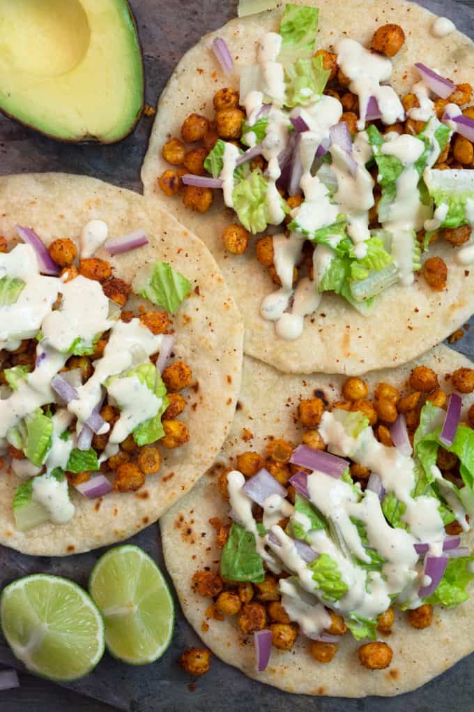 Top shot chickpea soft tacos. 3 seasoned chickpeas on a homemade flour tortilla topped with lettuce onions and a cheesy vegan ranch.