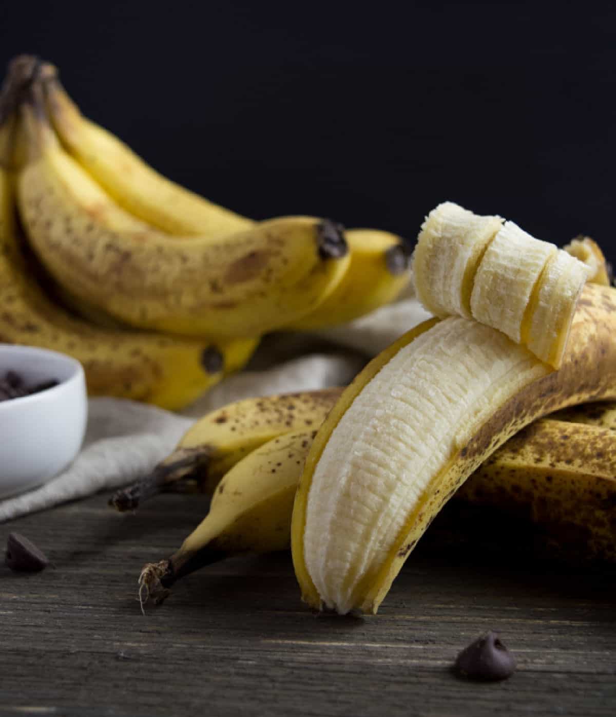Ripe bananas with one slightly peeled open.