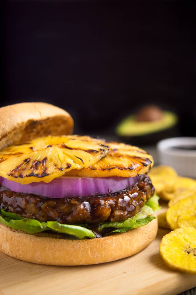 Grilled huli-huli vegan burger topped with red onion and grilled pineapple rings.