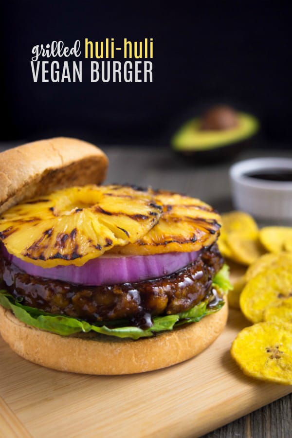 Grilled huli-huli vegan burger topped with red onion and grilled pineapple rings. It's served with a side of plantain chips.