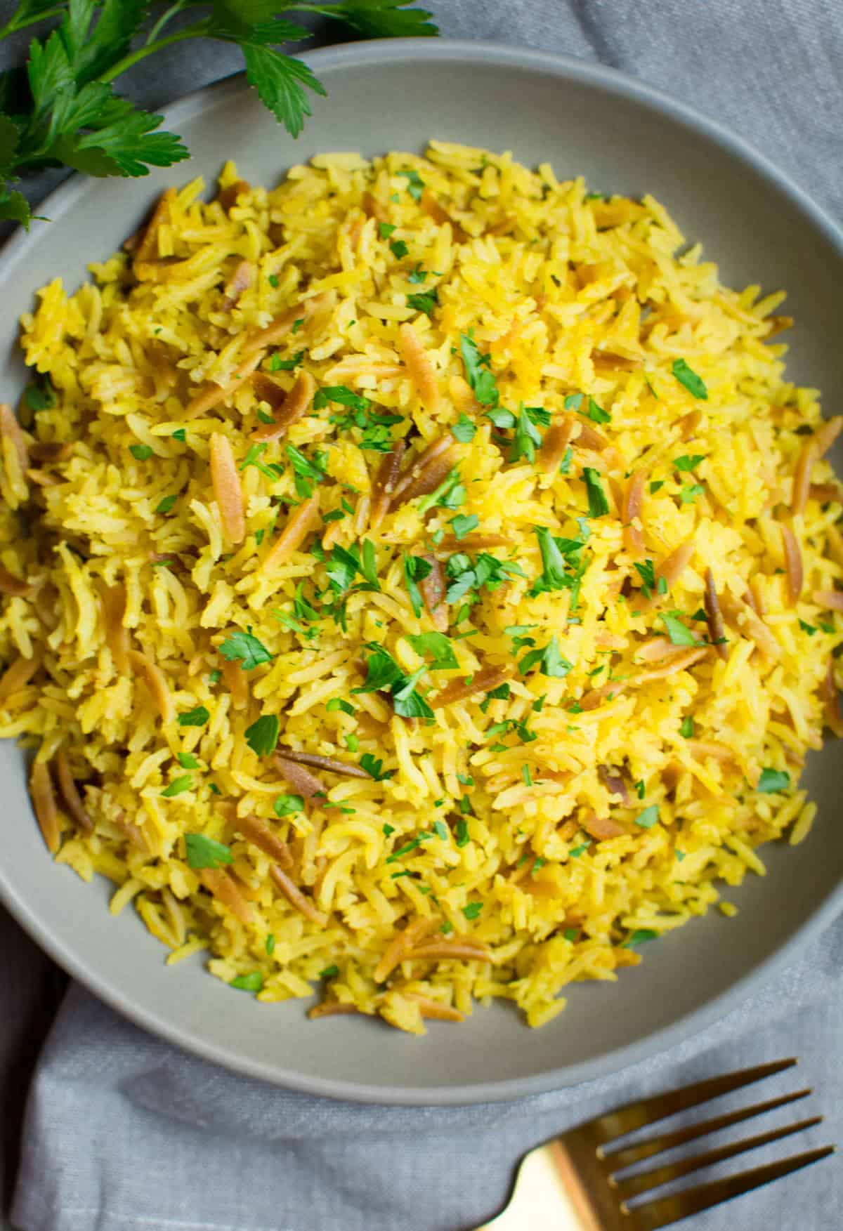 Looking down on a gray plate of rice pilaf topped with parsley.