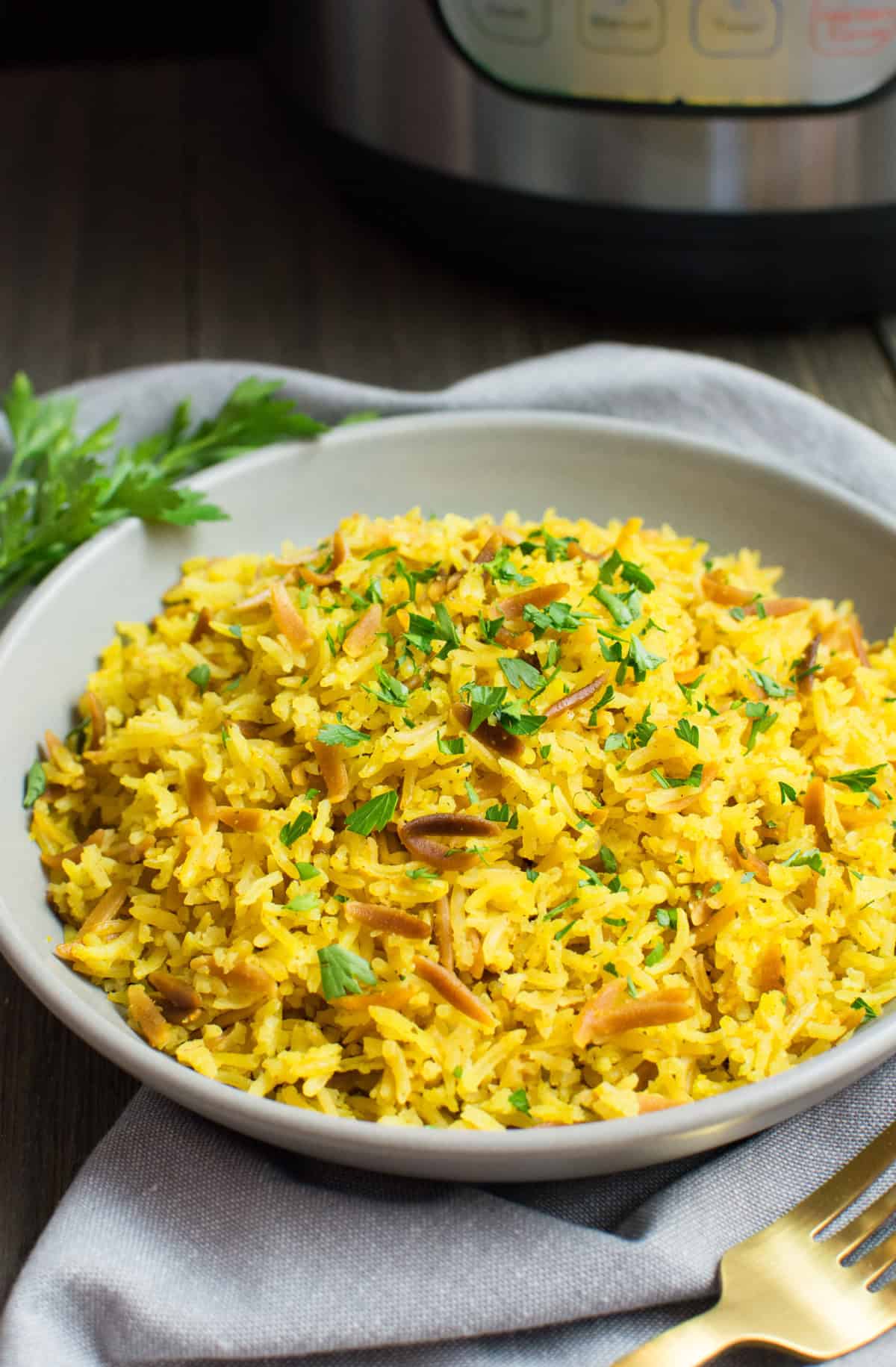 A plate of rice pilaf with an Instant Pot in the background.