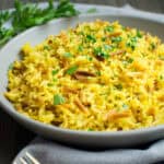 Yellow rice pilaf topped with fresh parsley.