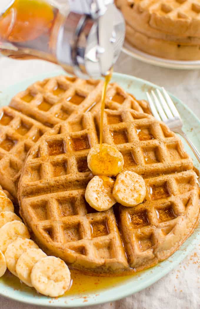 Cinnamon Vegan Waffles topped with banana slices and drizzled with maple syrup.