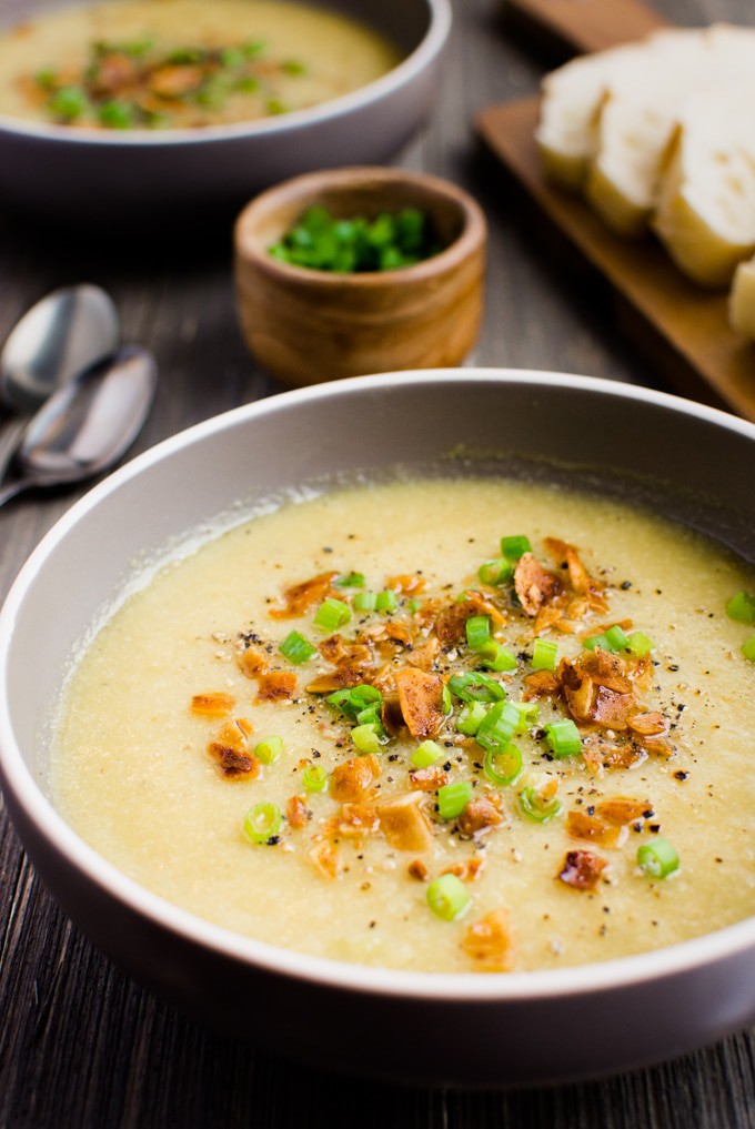Vegan cauliflower leek soup topped with vegan bacon and green onions. It's served with a fresh baked loaf of french bread.