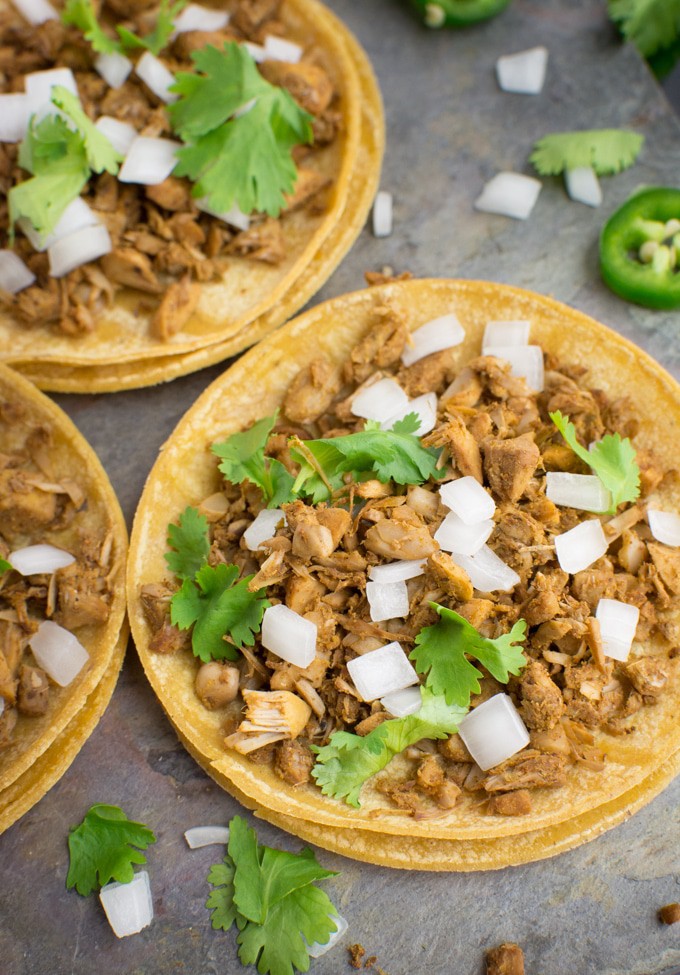 Three corn tortillas filled with jackfruit and topped with fresh cilantro and diced onion.