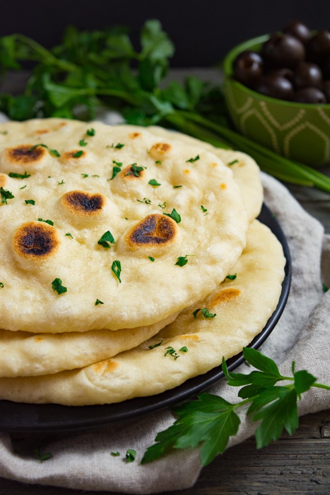 Soft vegan naan bread stacked on a plate.