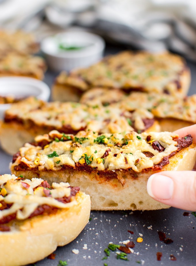 A hand grabbing a slice of vegan french bread pizza.