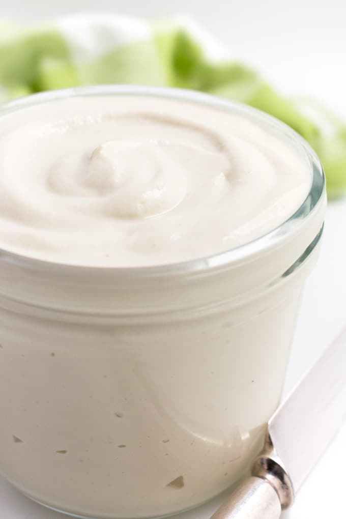 Vegan mayo in a glass jar with a knife off to the side.