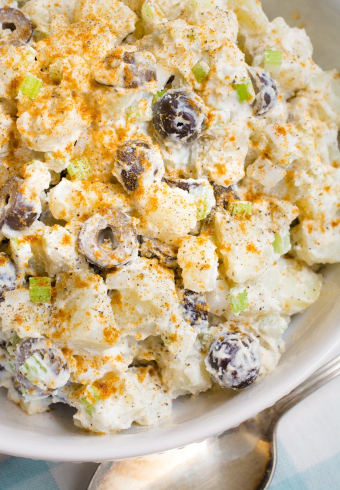 A top view of classic vegan potato salad with chopped olives and sprinkled with paprika.