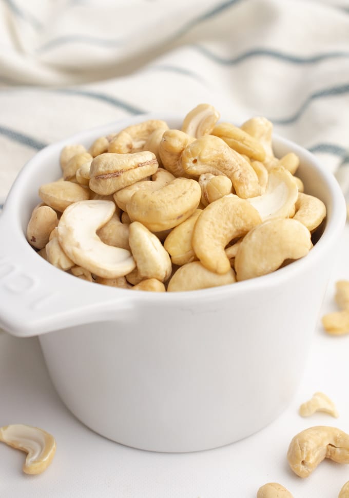 Raw cashews in a measuring cup.