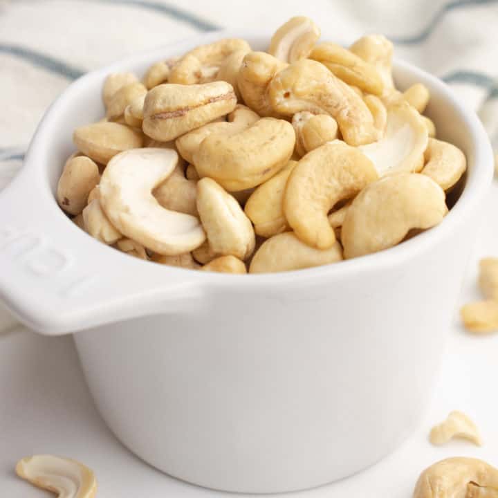 Raw cashews in a measuring cup.