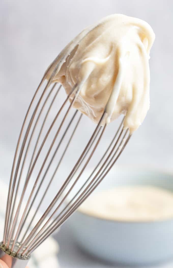 Thick and creamy vegan cashew frosting whipped up on the tip of a whisk.