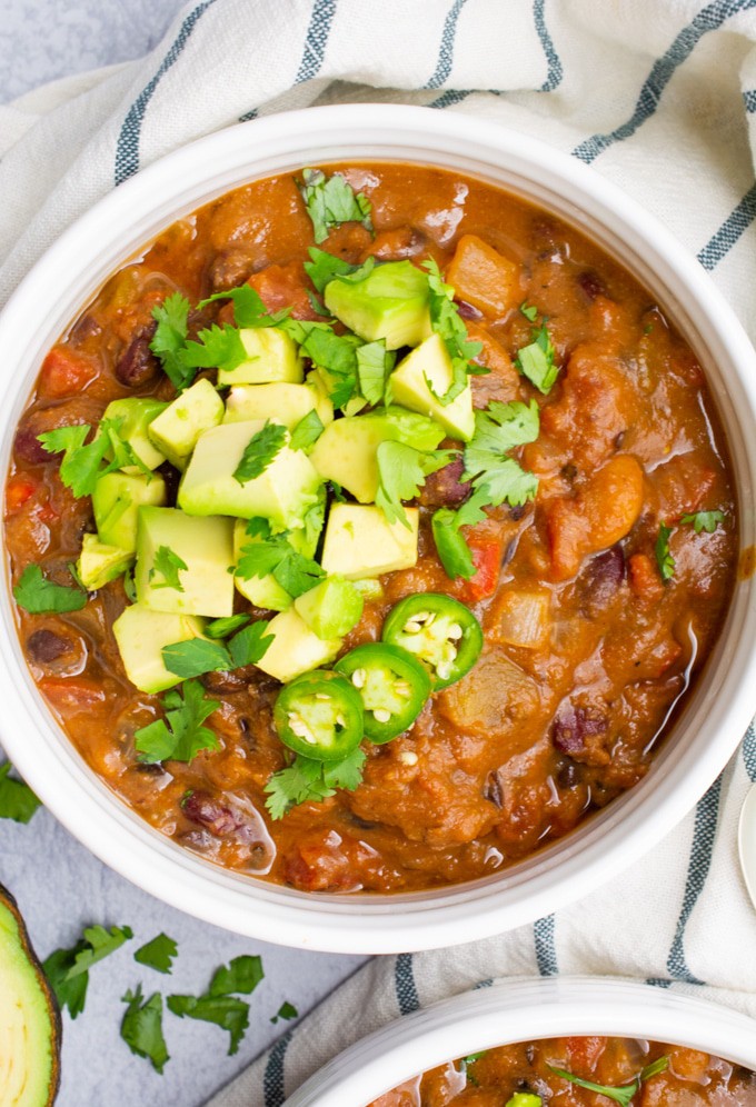 Vegan bean chili in a white bowl with toppings.